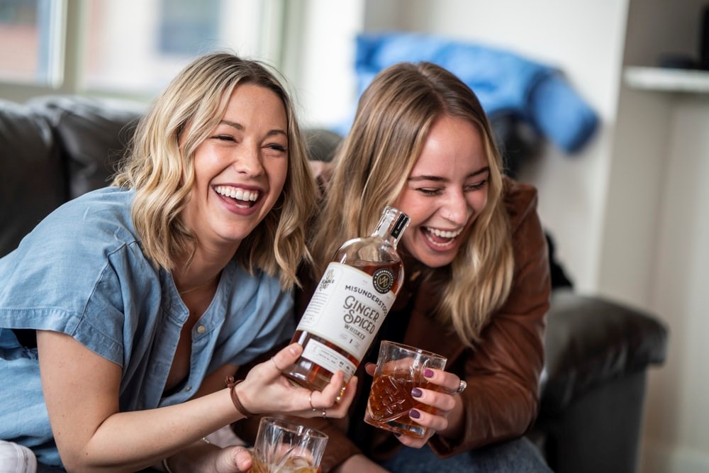 Two Women Laughing at Something While Sharing a Bottle of Ginger Spiced Whiskey